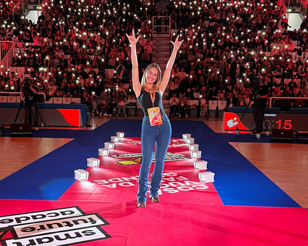 photos of Carolina Tedeschi standing with arms raised that make the symbol of rock with people on the stands holding torches in their hands