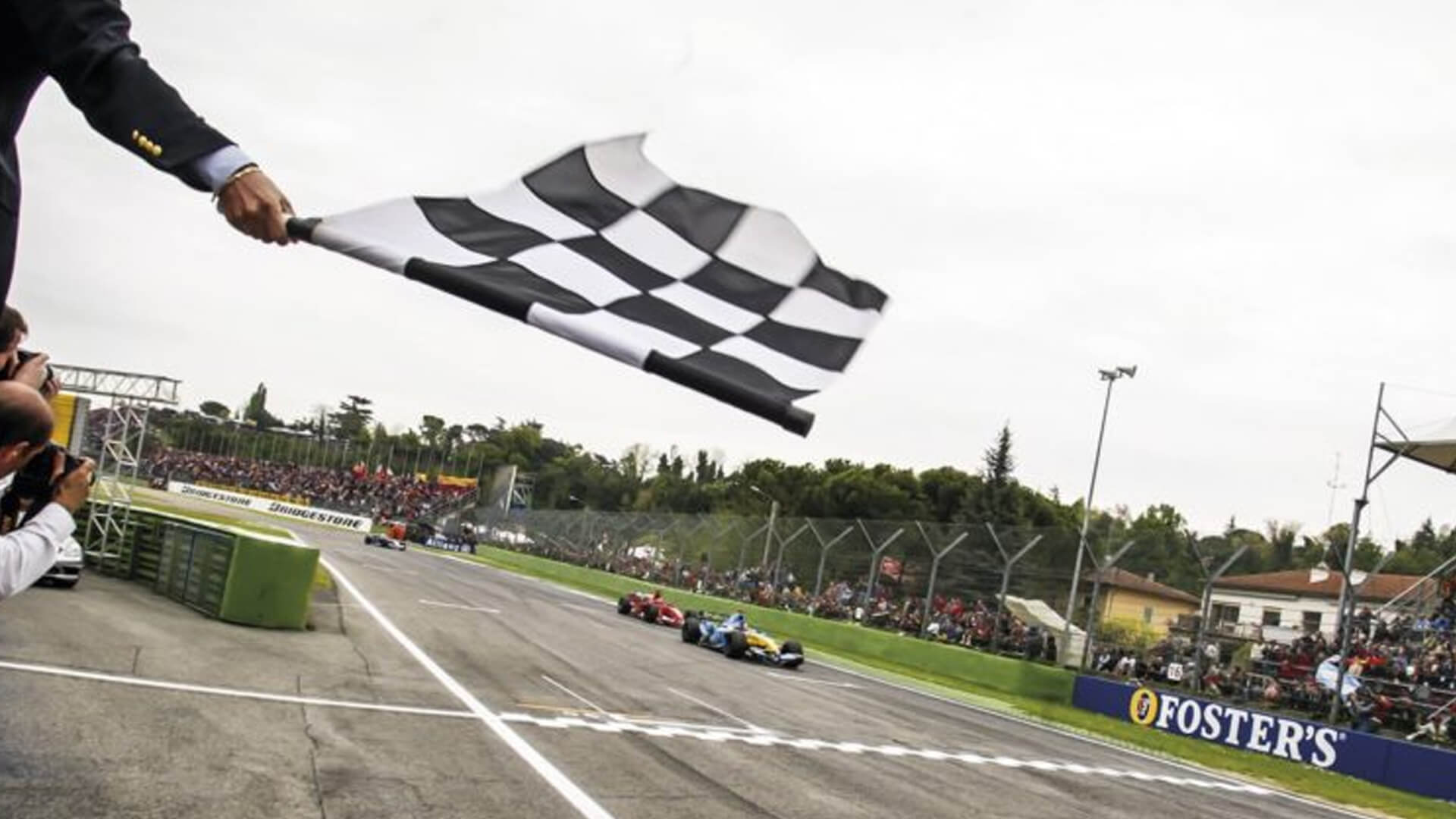 In the foreground, a checkered flag waving at the finish line of a formula one grand prix