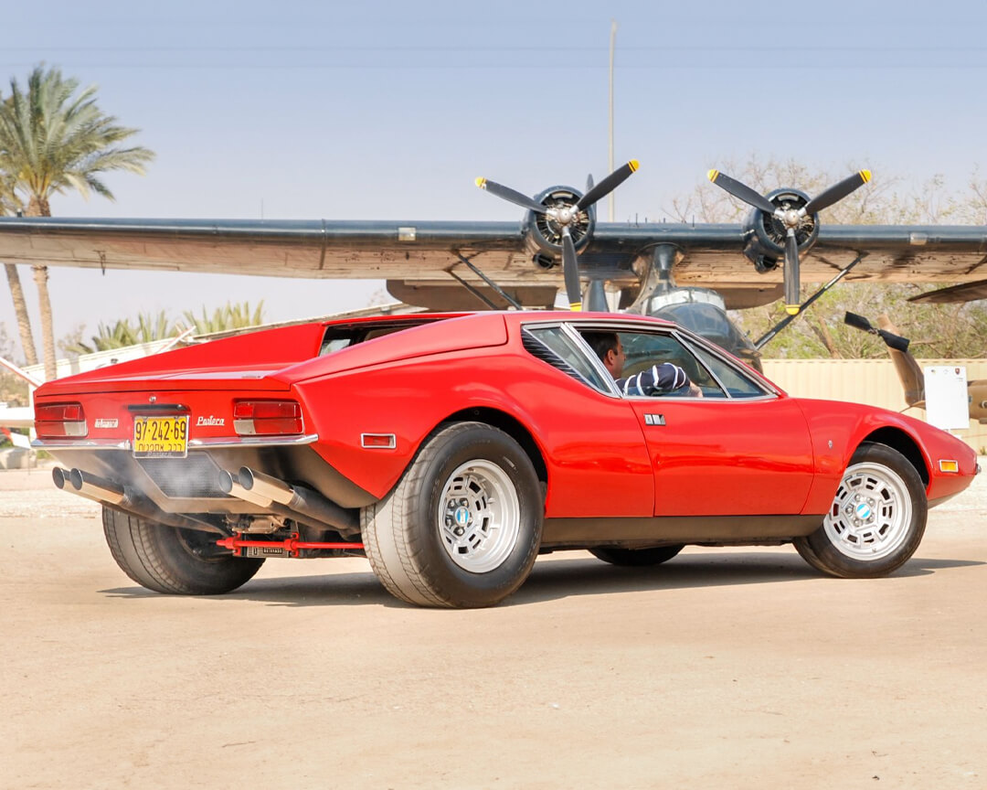 Vista posteriore laterale di una de tomaso pantera rossa con i tubi di scarico fumanti