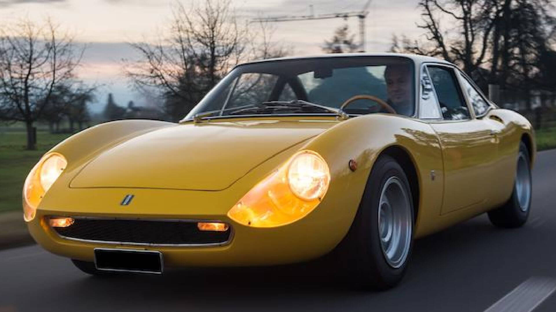 De Tomaso vallelunga in colorazione gialla che sfreccia a fari accesi su una strada