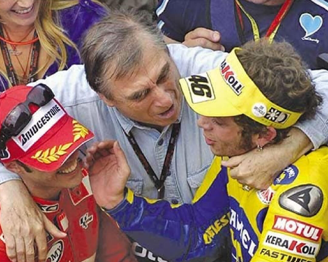 Doctor Costa between Valentino Rossi and Loris Capirossi who embraces both after a race