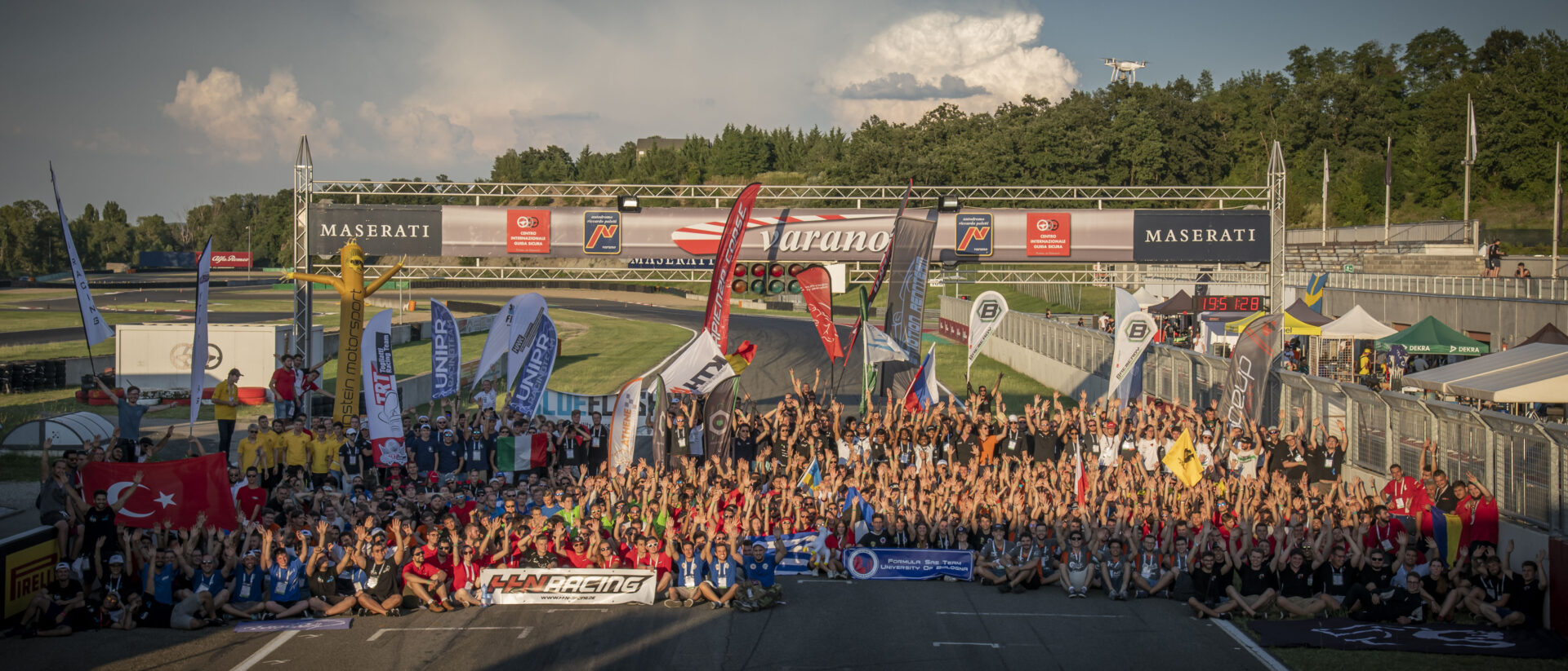 foto di gruppo di tutti i team partecipanti alla Formula SAE all'Autodromo di Varano de Melegari con bandiere e mani alzate