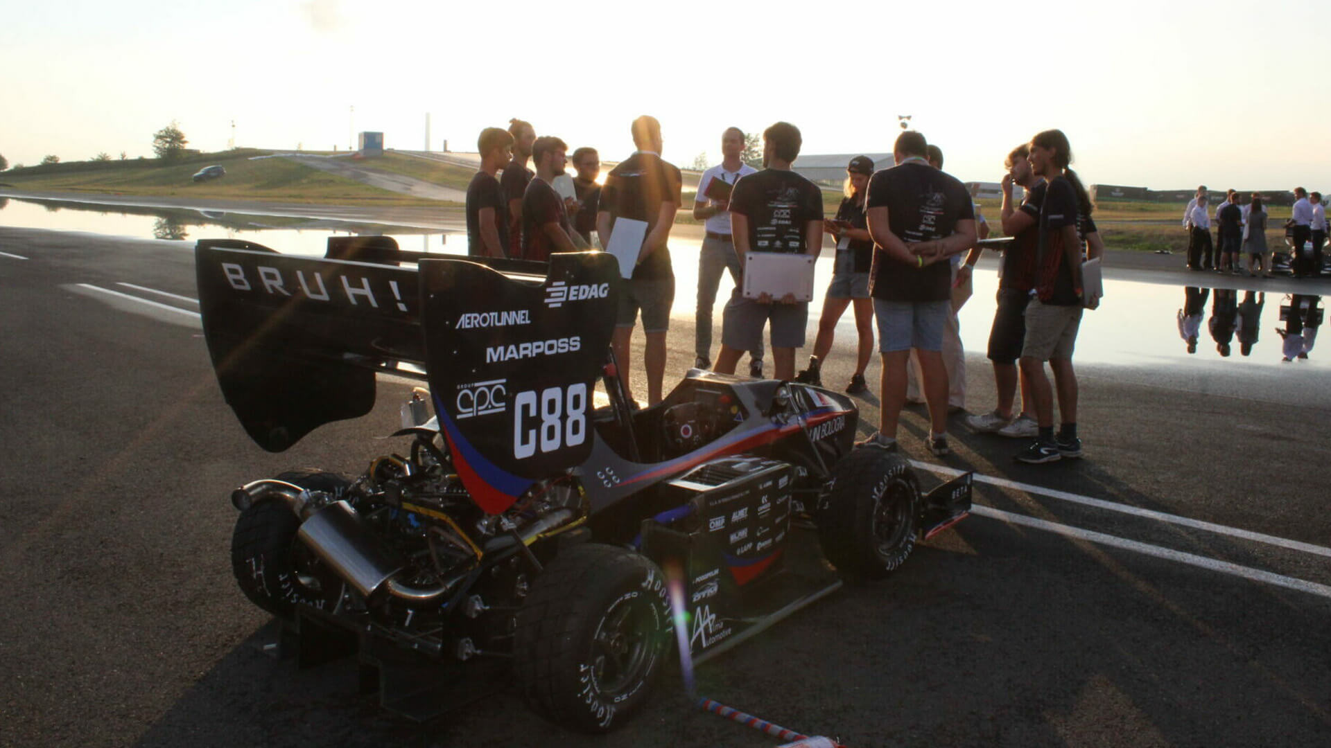 Prototipo di auto monoposto con gruppo di studenti sul circuito di prova