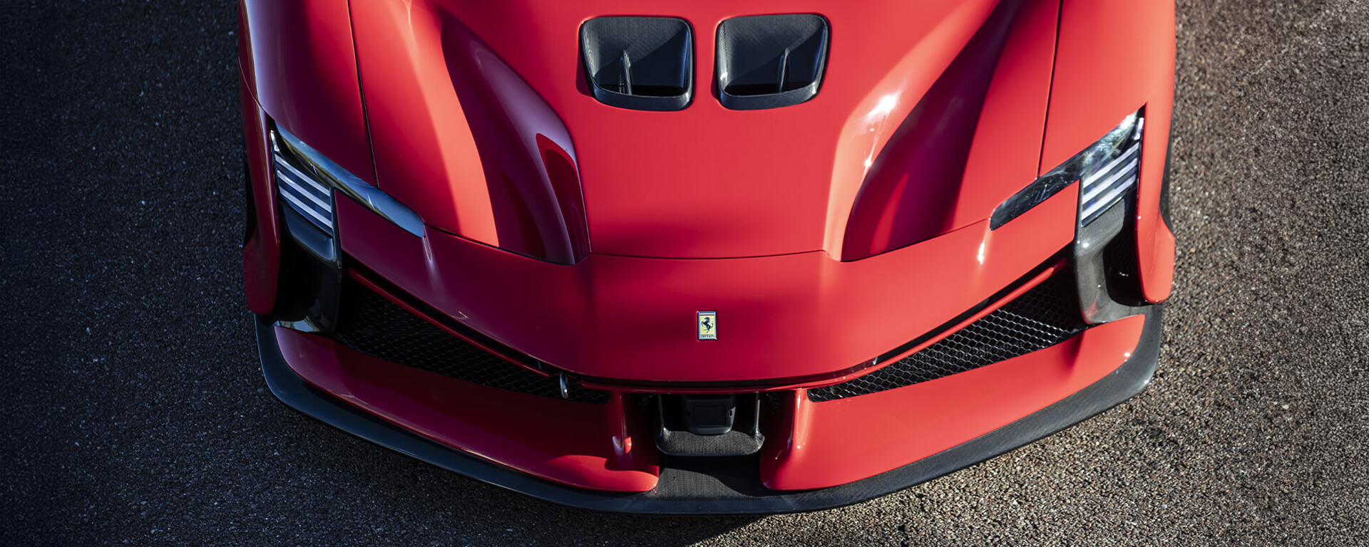 muso di una Ferrari supercar rossa dall'alto con asfalto
