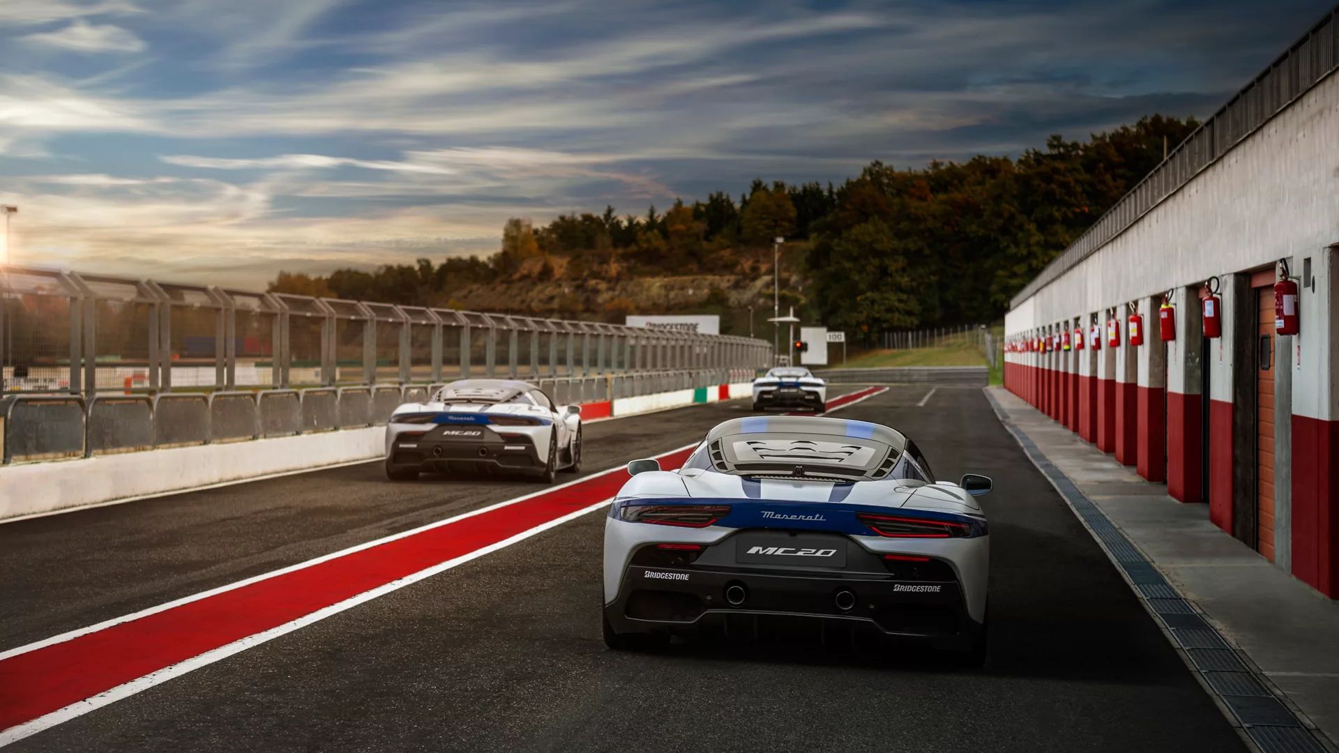 Tre Maserati escono dal rettilineo dei box di un circuito.