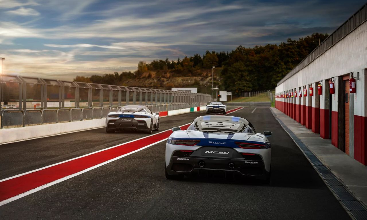 Tre Maserati escono dal rettilineo dei box di un circuito.