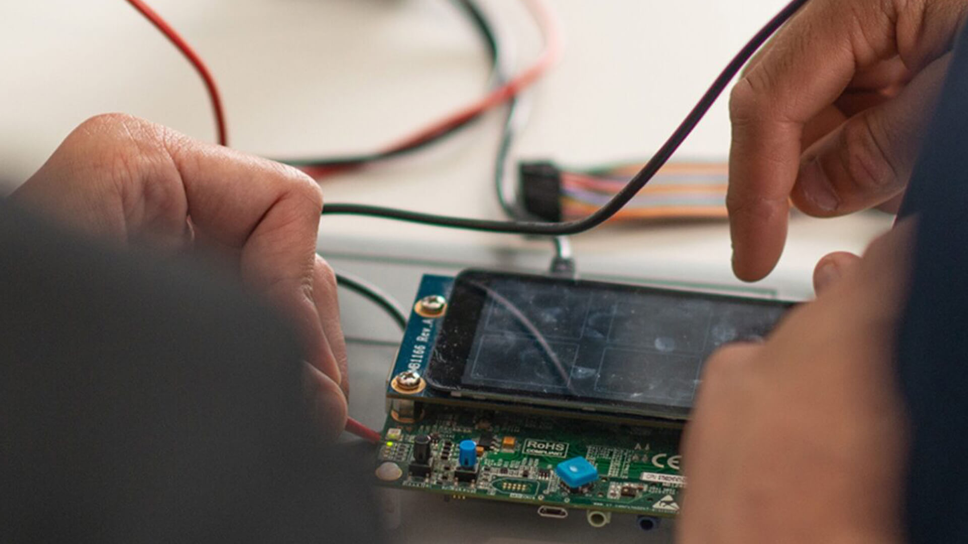 mani che lavorano su un display attaccato ad un chip collegato a dei cavi