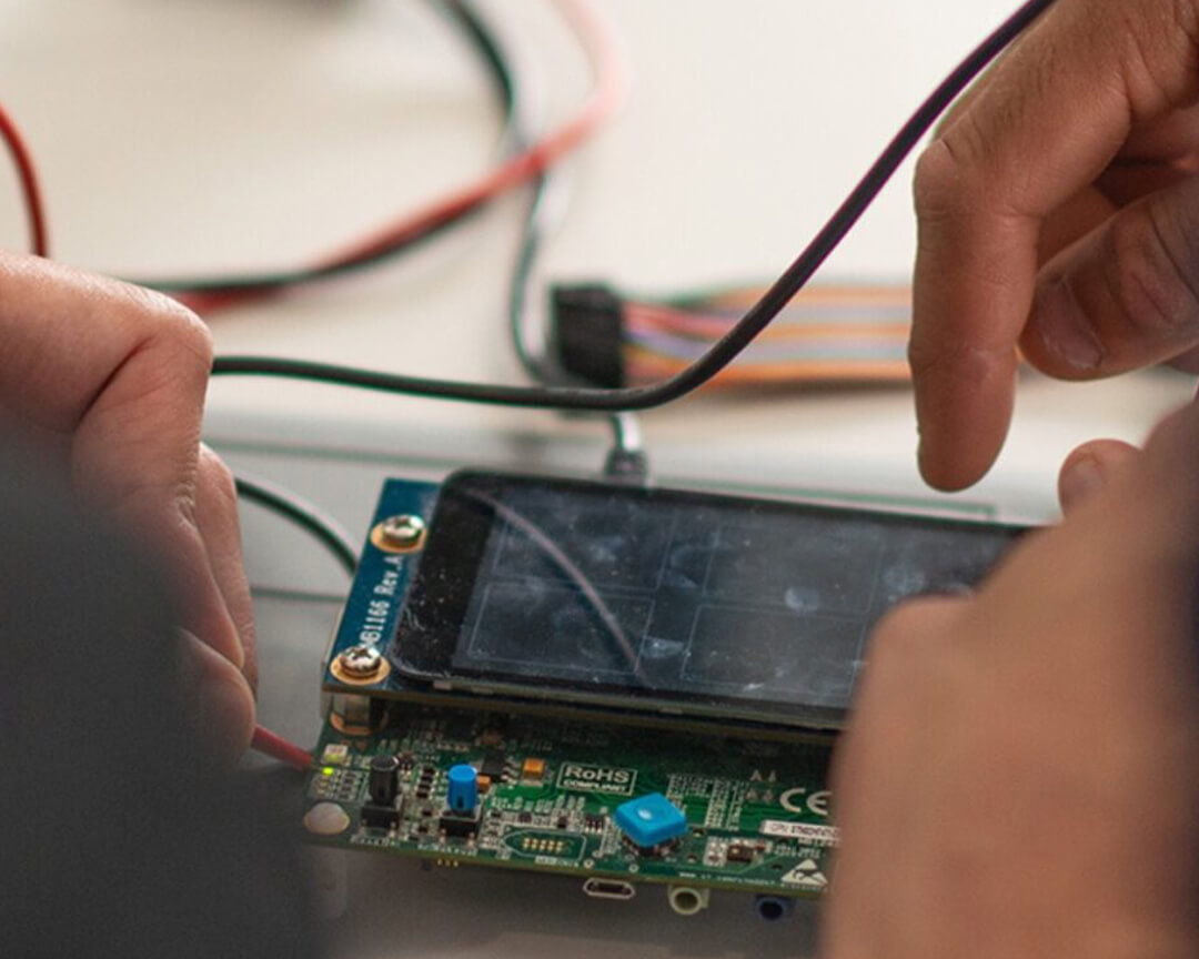 mani che lavorano su un display attaccato ad un chip collegato a dei cavi