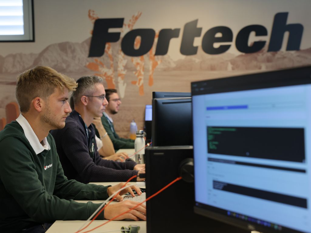 Dipendenti della Fortech in ufficio di profilo davanti ai loro monitors.