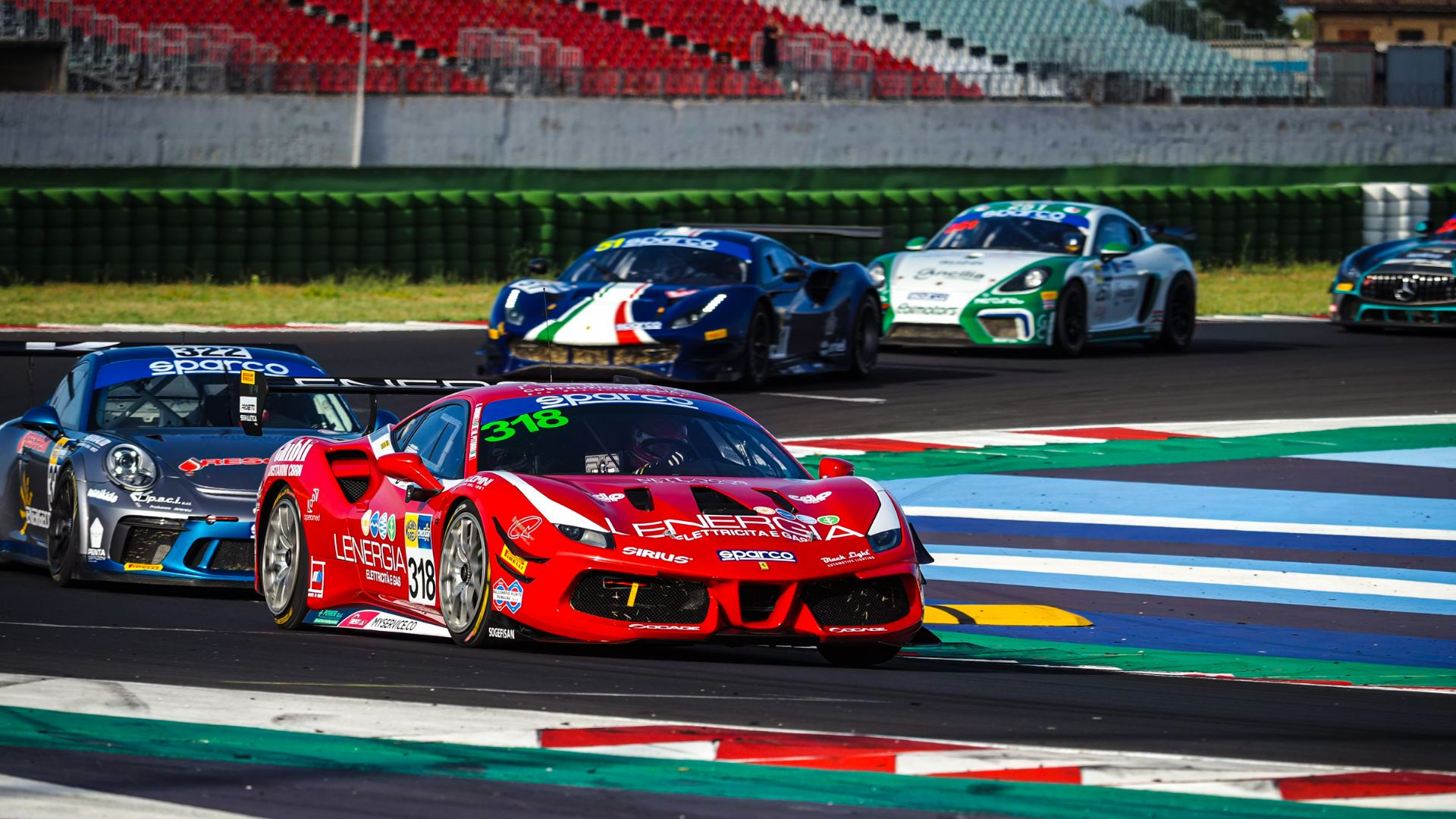 Ferrari da corsa colore rosso sfreccia in pista seguita da altre macchine.