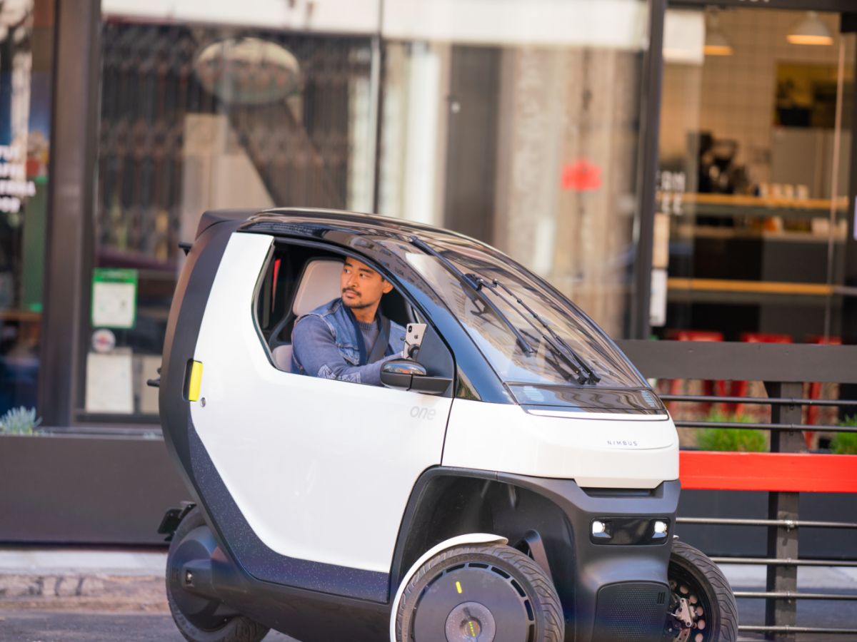 Ragazzo guida una piccola vettura elettrica che sembra una Smart.