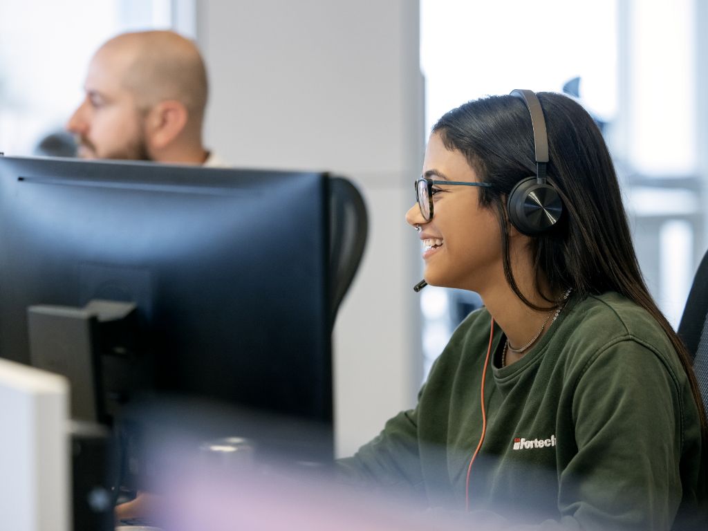 Una dipendente sorridente della Fortech davanti al computer in ufficio.