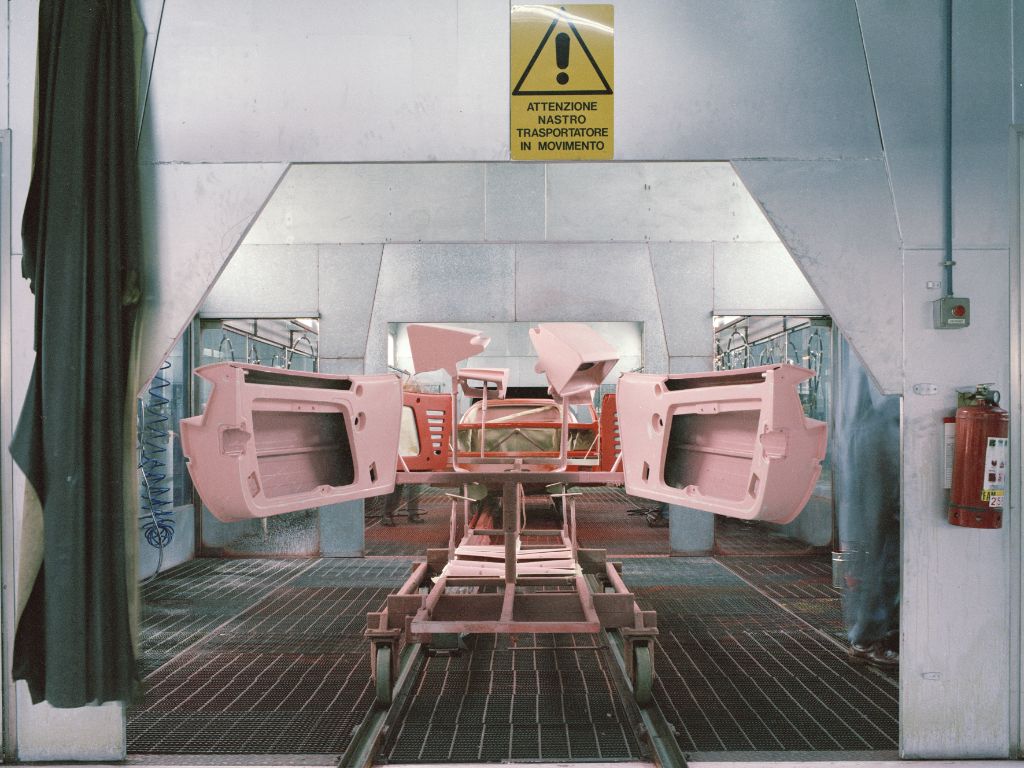 Pezzi di una vettura Ferrari nella sala di verniciatura della fabbrica, di colore rosa.