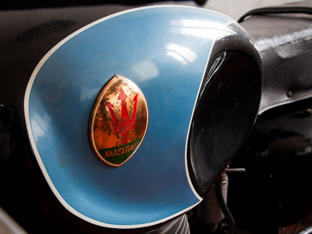 Primo piano sul logo Maserati di una moto d'epoca.