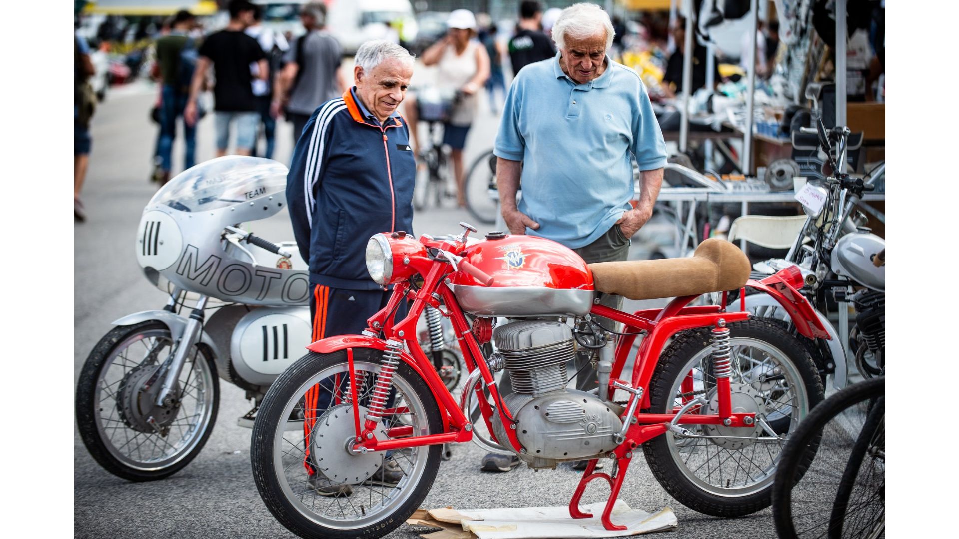 Due anziani amici guardano una moto d'epoca.