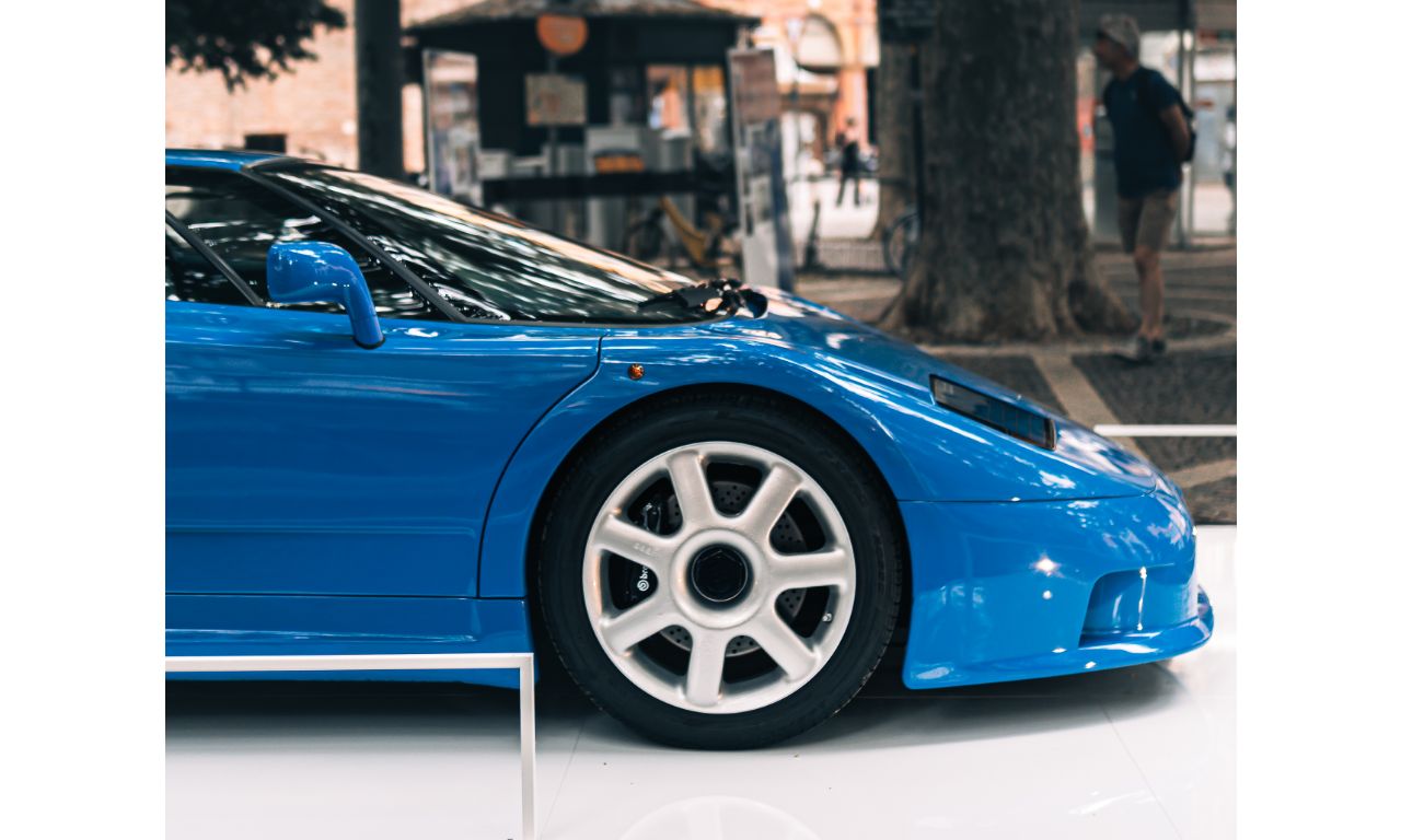 Profilo di una Bugatti su di un piedistallo in una piazza.