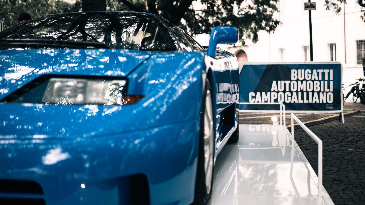 Primo piano di un fanale Bugatti con sullo sfondo l'insegna della Bugatti Automobili Campogalliano.