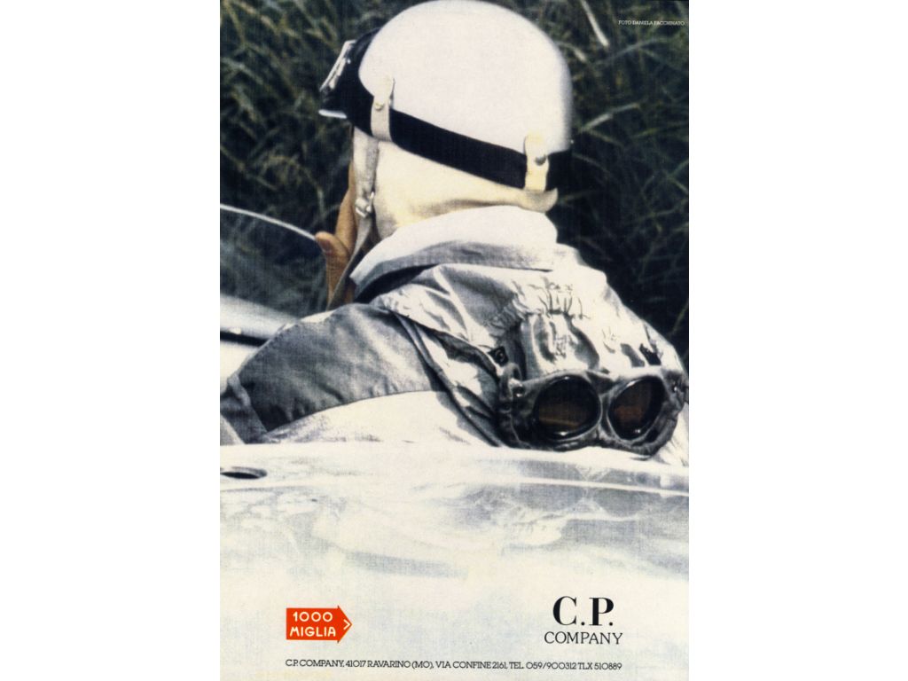 Pilota da dietro con le lenti del suo cappuccio C.P. Company ben in vista, in una locandina della Mille Miglia del 1988.