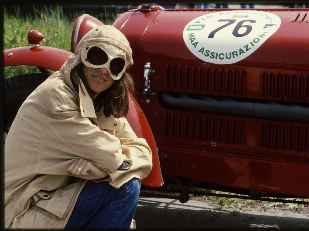 Ragazza col cappuccio della giacca Mille Miglia di C.P. Company davanti a una vettura.