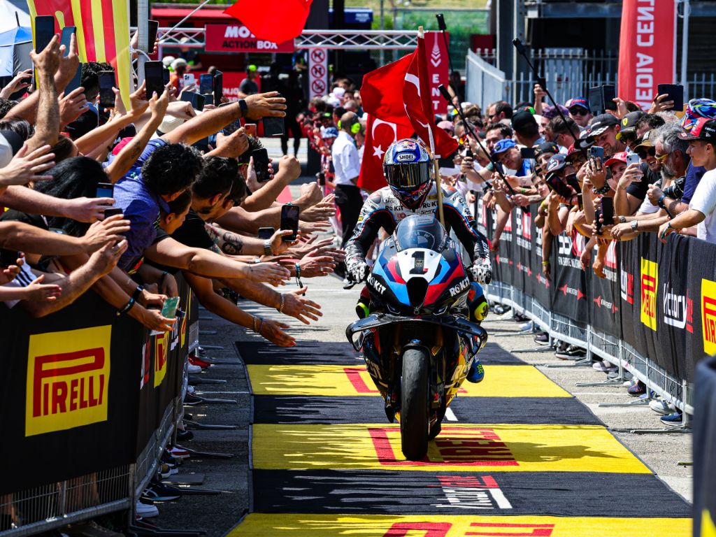 Toprak Razgatlioglu sulla sua moto, festeggia circondato dalla folla.