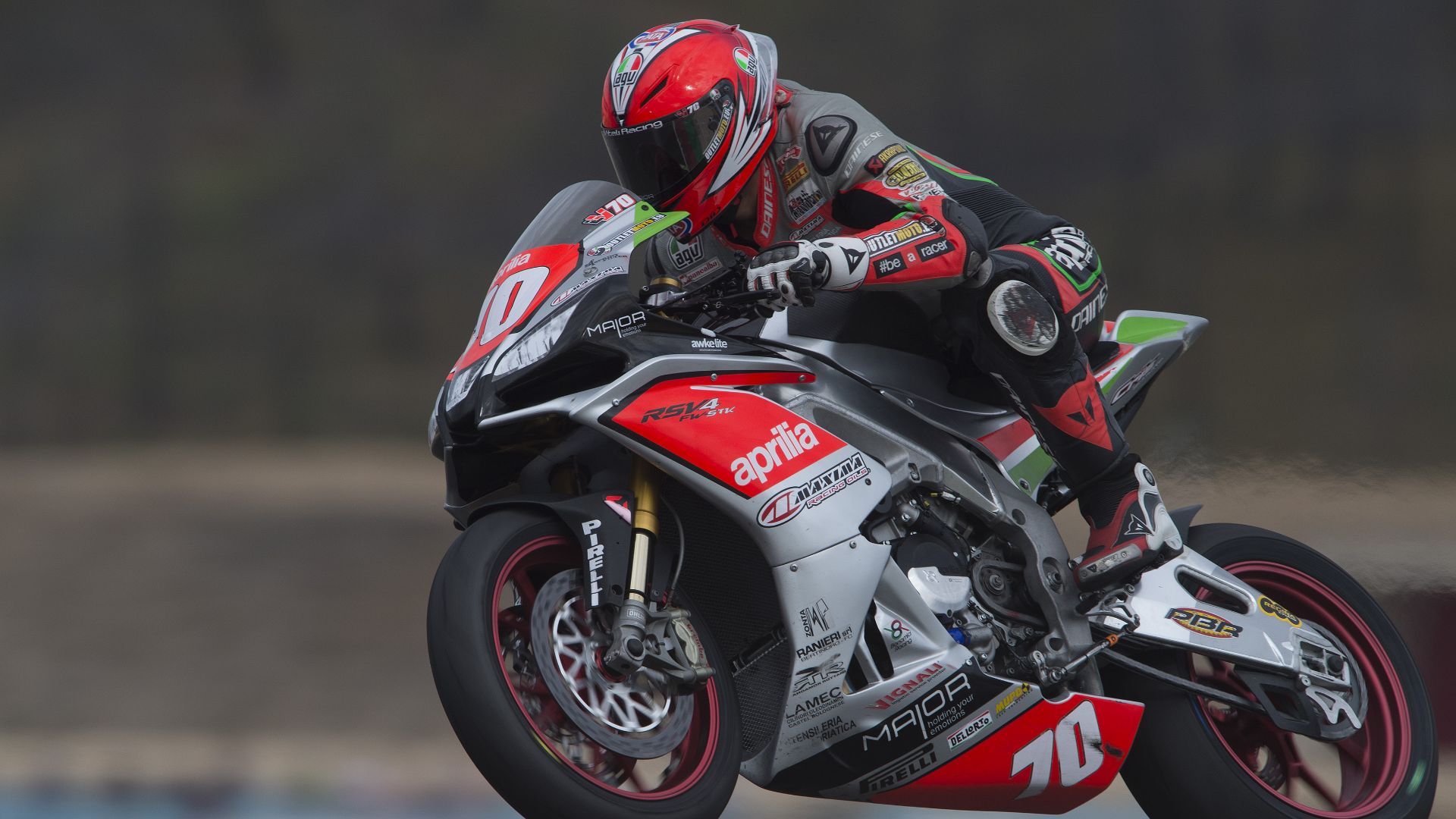 Primo piano di un pilota su una moto Aprilia in corsa.