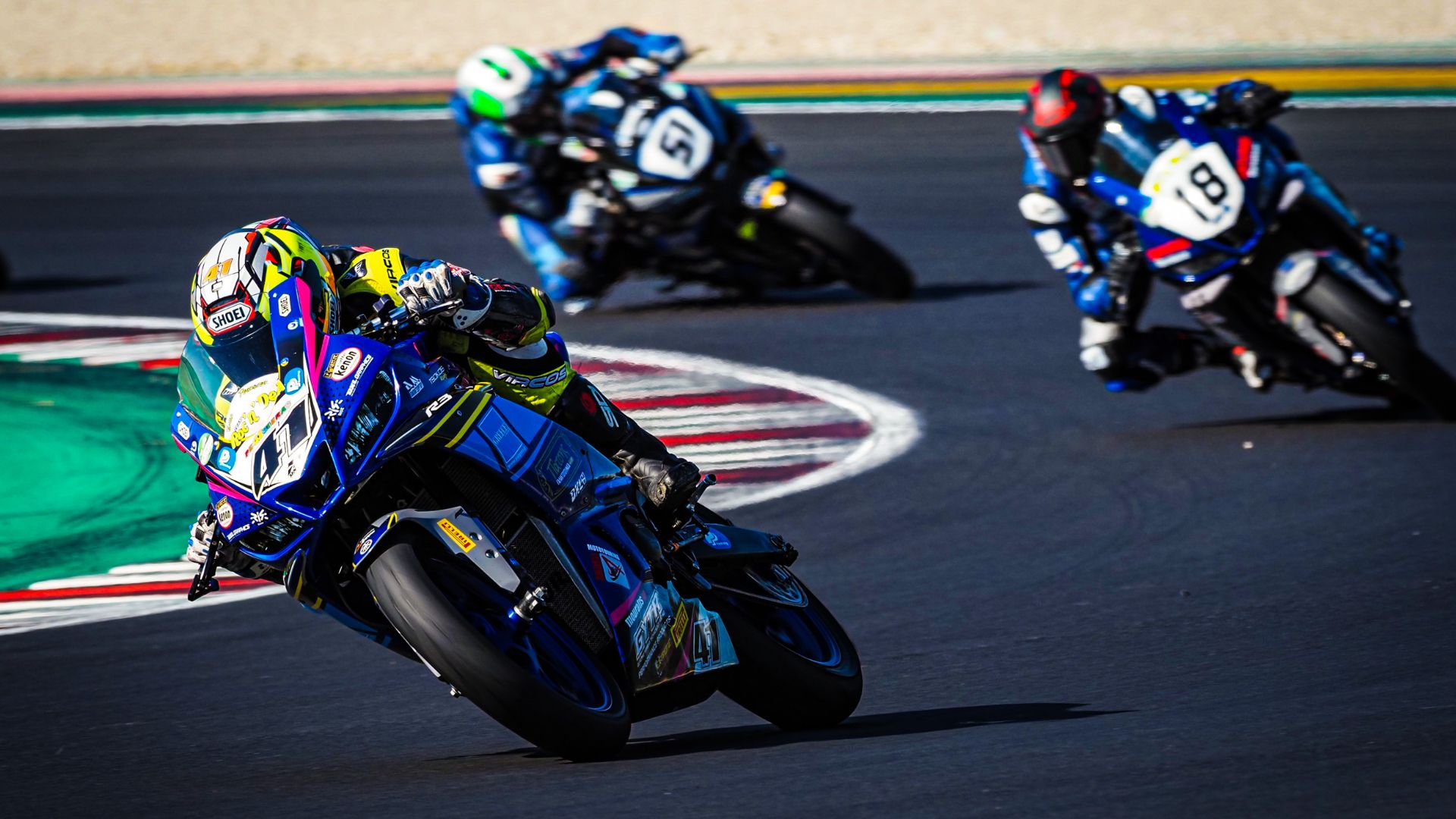 Tre piloti si rincorrono in moto lungo una curva del Misano World Circuit.