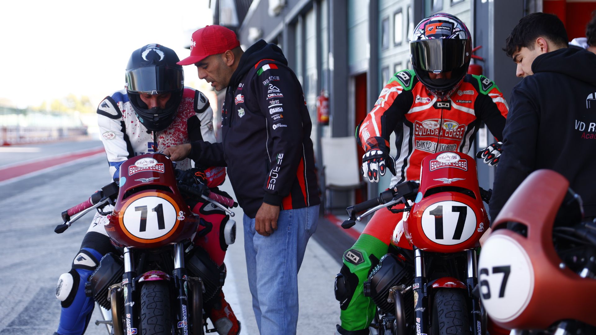 Due piloti a bordo delle loro moto d'epoca nel paddock di Misano.
