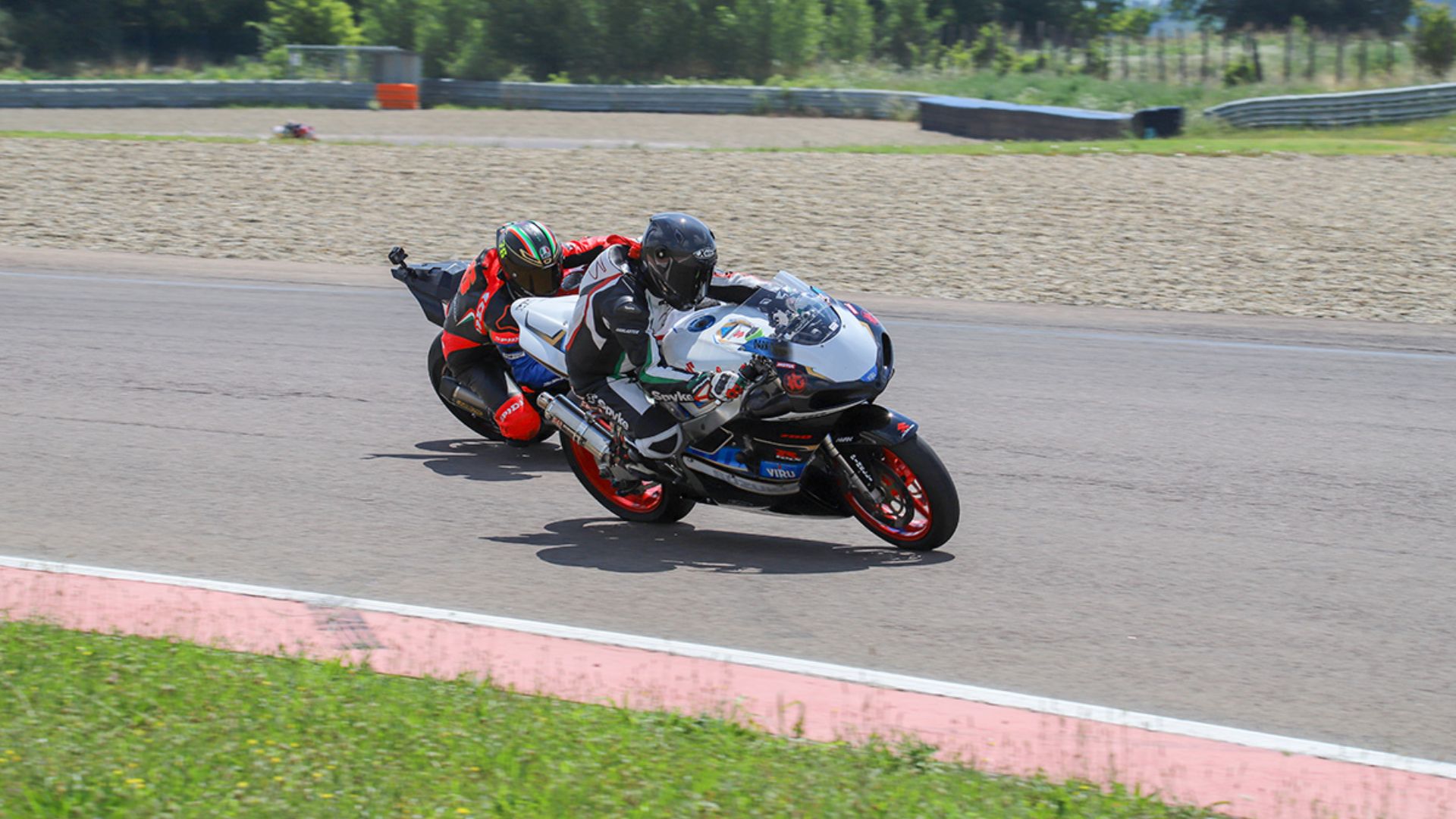 Due piloti si fronteggiano sulle loro moto sul tracciato dell'Autodromo di Modena.