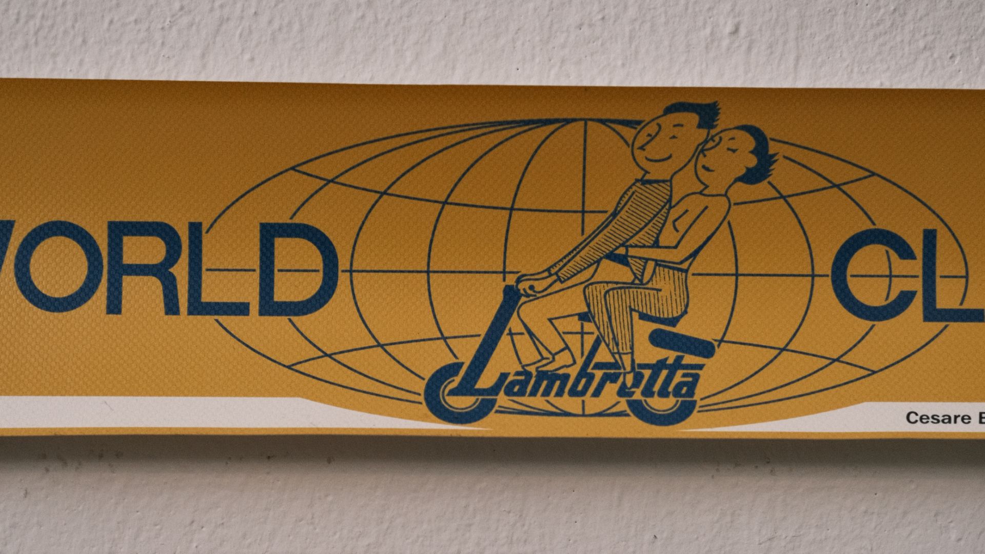 Grafica vintage gialla con la scritta "World Club Lambretta" e un'illustrazione di una coppia su uno scooter.