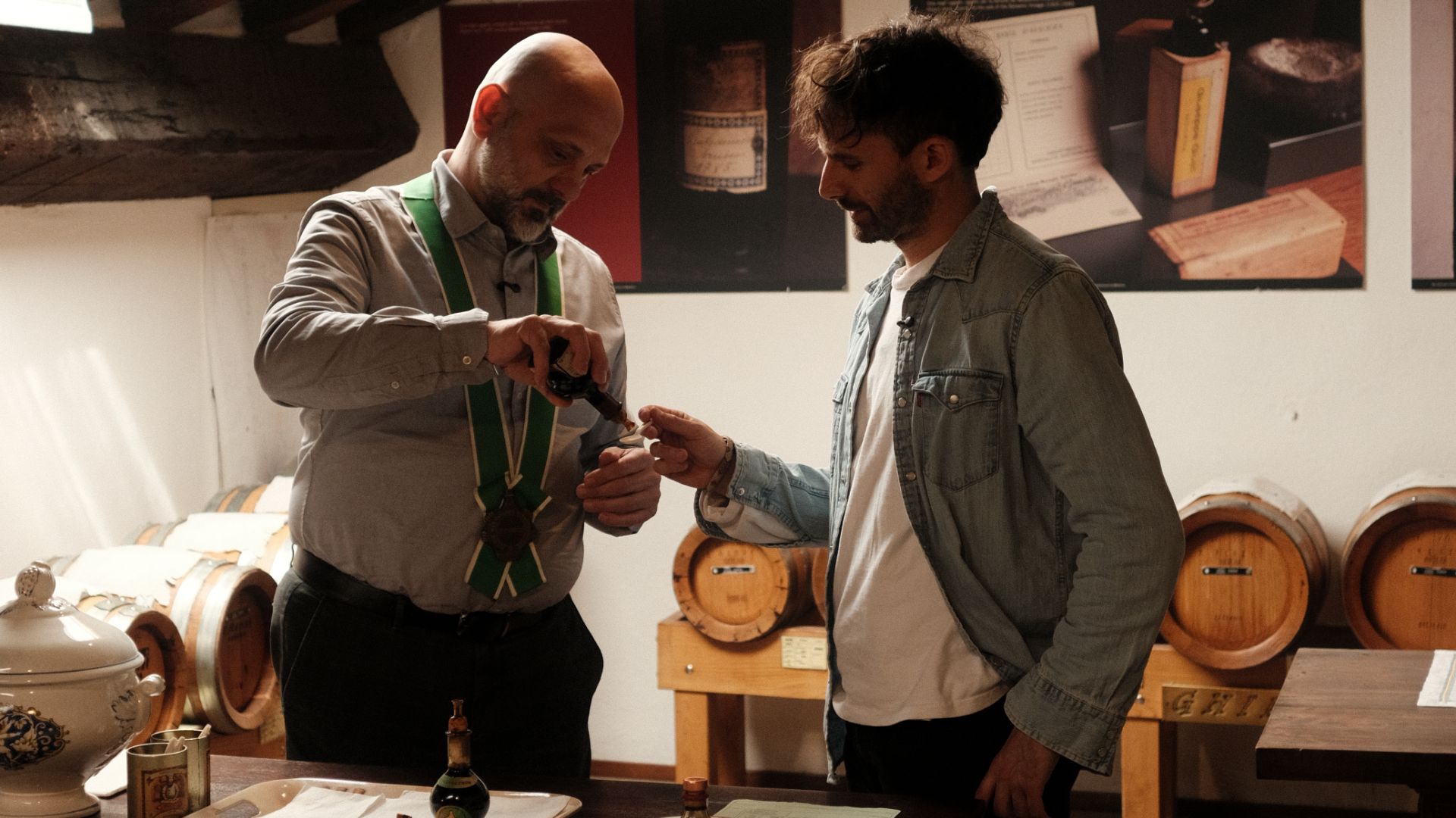 Un uomo fa assaggiare ad un altro l'aceto balsamico tradizionale di Modena su un cucchiaino, all'interno del sottotetto dell'acetaia comunale di Modena.
