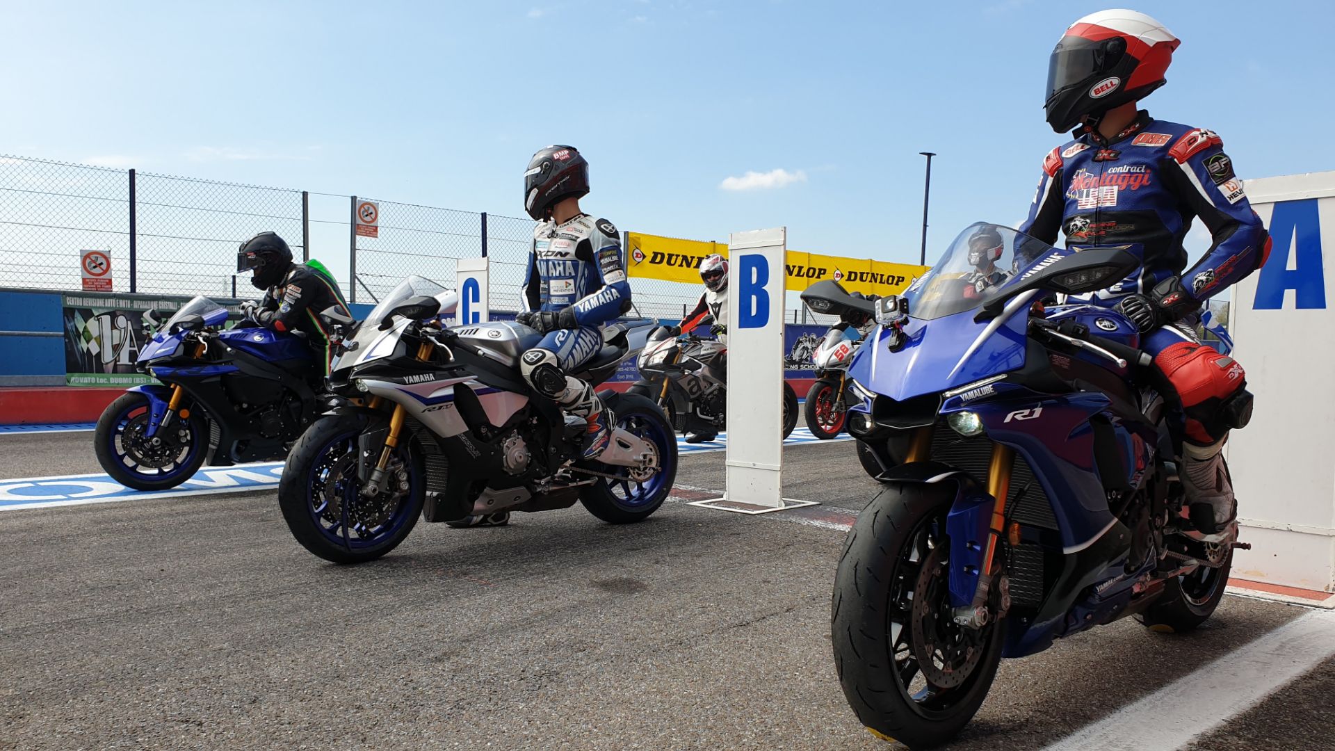 Piloti su moto sportive Yamaha R1 nella corsia box durante un corso di guida in pista.