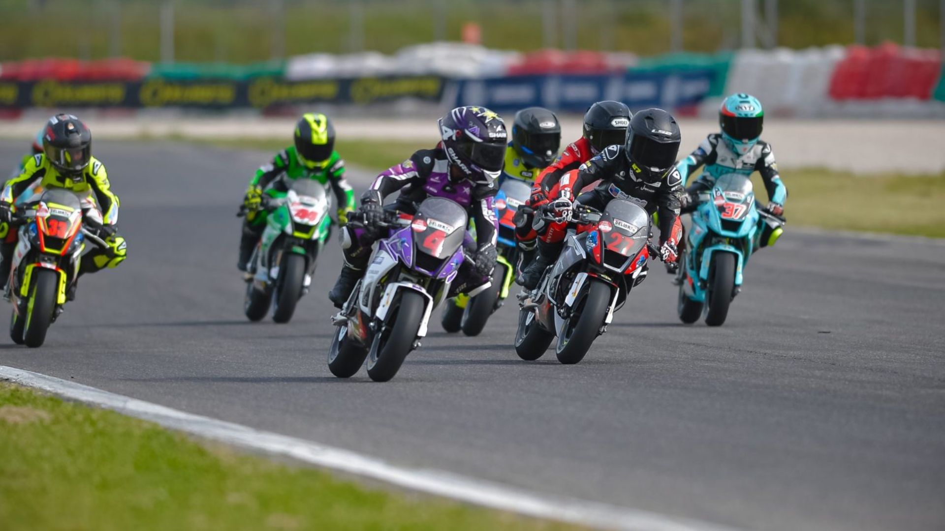 Piloti del CIV Junior in sella a moto MiniGP durante una gara in pista mentre affrontano una curva in gruppo.