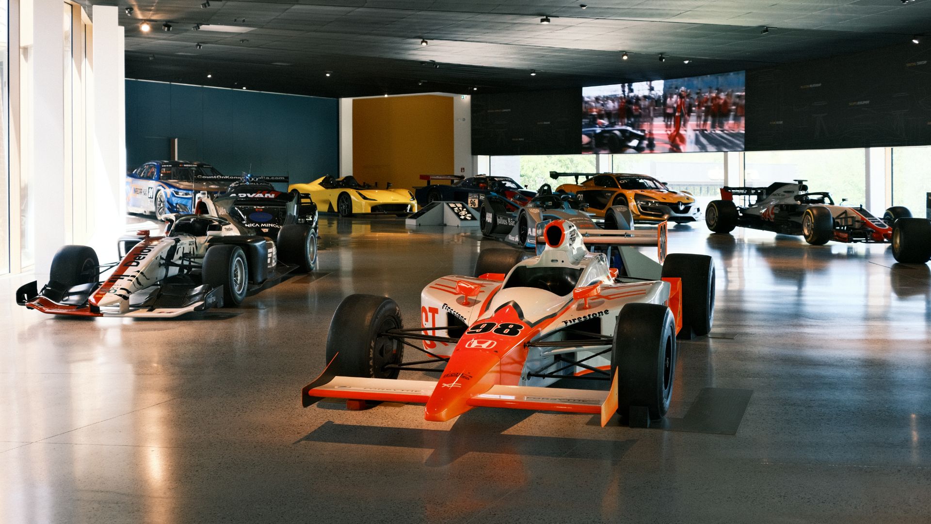 Monoposto IndyCar e auto da corsa storiche esposte nella grande sala del museo Dallara Academy a Parma.