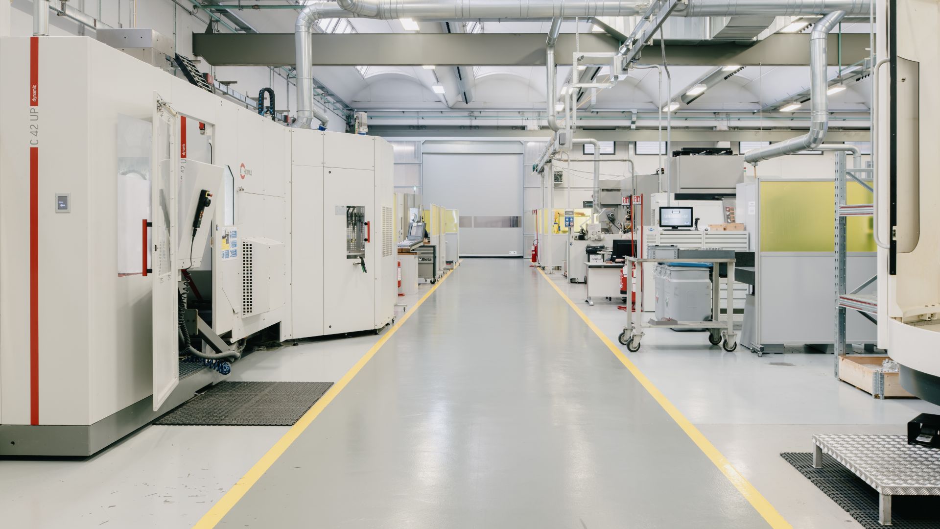 Corridoio centrale di un'officina meccanica di precisione con centri di lavoro CNC Hermle avanzati