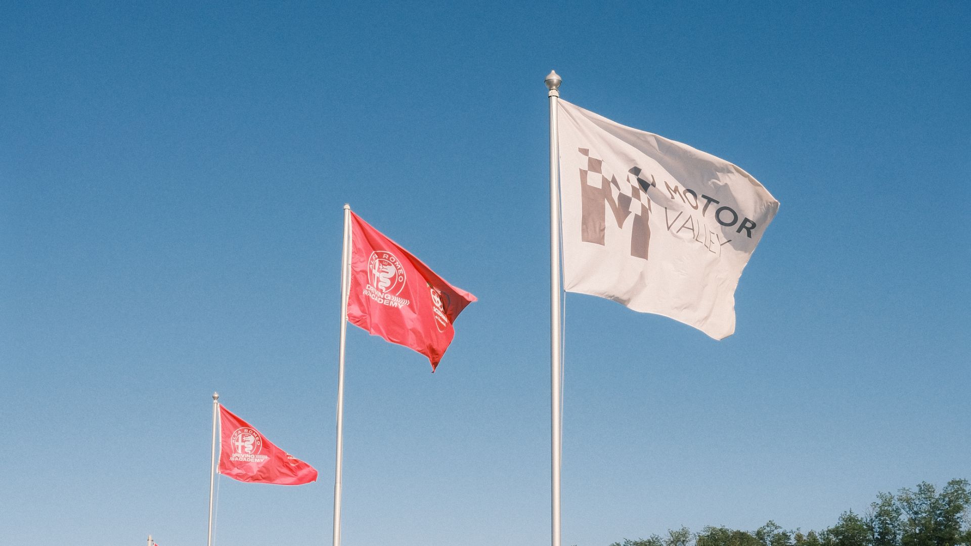 Bandiere ufficiali di Motor Valley e della Alfa Romeo Driving Academy che sventolano nel circuito di Varano.