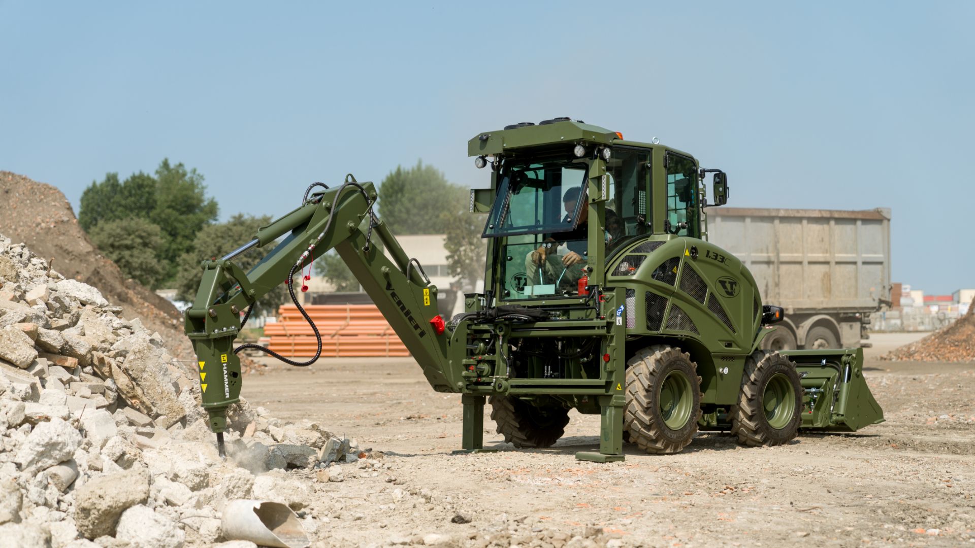 Terna militare Venieri 1.33C verde equipaggiata con martello demolitore idraulico in azione su macerie