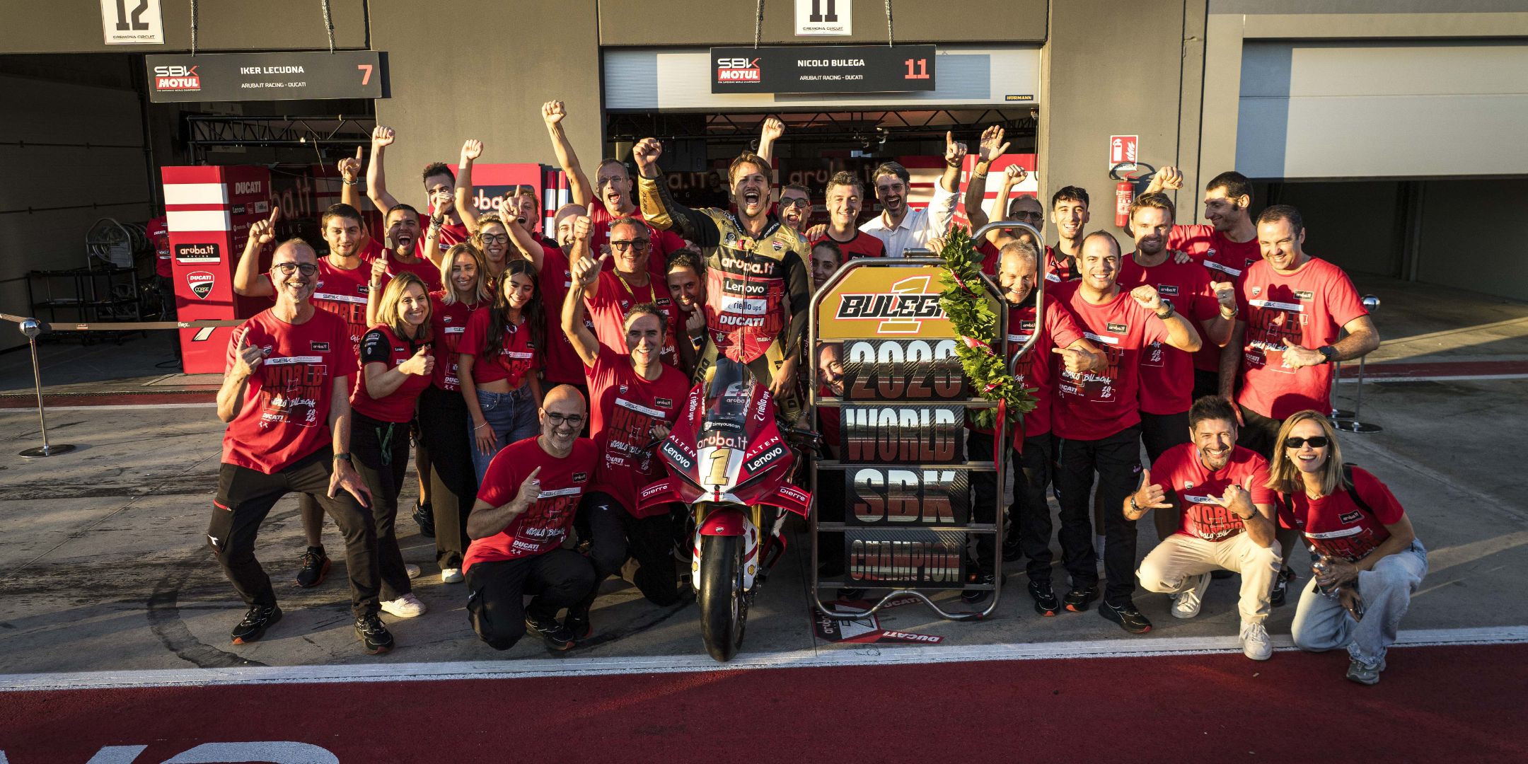 Nicolò Bulega celebra la vittoria del titolo di Campione del Mondo 2023 nei box, circondato dai festeggiamenti di tutto il team Aruba.it Racing Ducati.