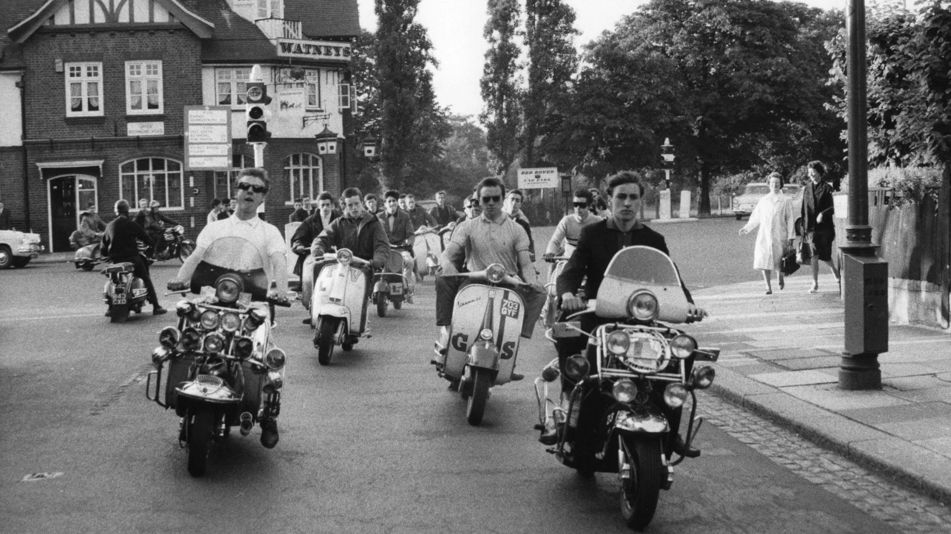 Giovani Mod anni '60 in strada con scooter d'epoca e abbigliamento vintage.