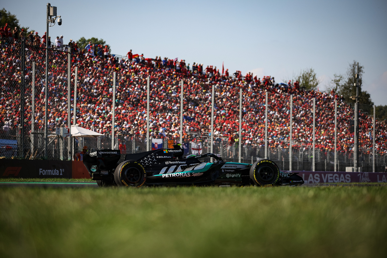 La vettura di Formula Uno di Kimi Antonelli in pista a Monza con la tribuna gremita sullo sfondo.